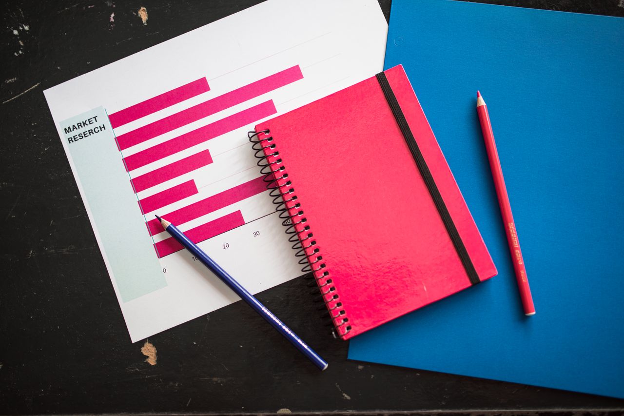 The Art of Drawing Readers In: Your attractive post title goes here Overhead view of business chart with red notebook and colored pencils on table.